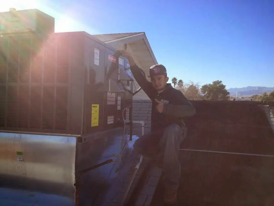 HVAC technician performing Air Duct Cleaning on a rooftop unit in Burkburnett